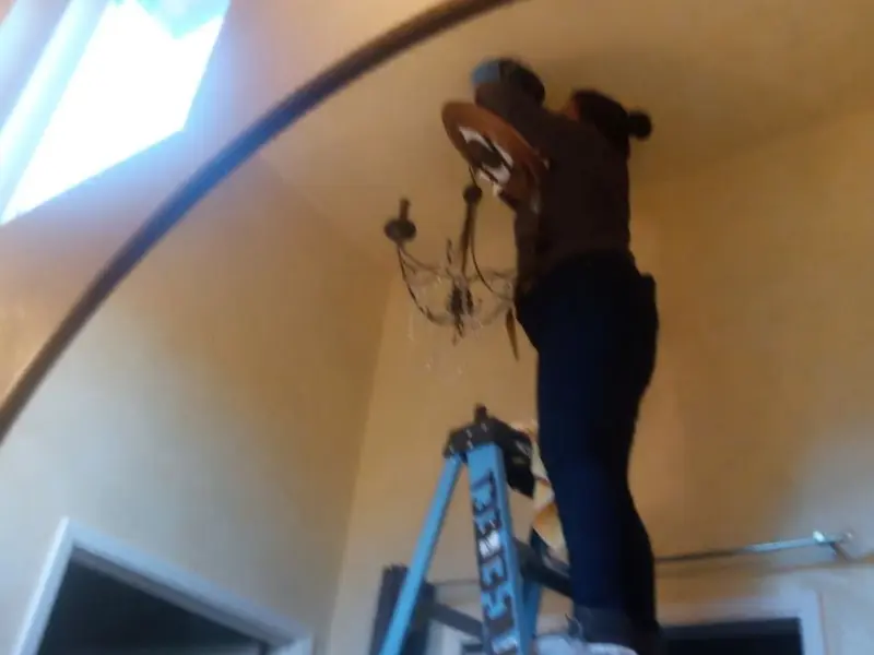 Electrician installing a chandelier in a Horace residence